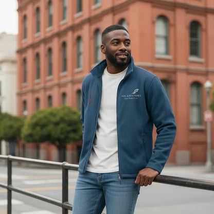 A man wearing a blue Fog & Foundry full-zip fleece jacket with a stand-up collar, standing in a city setting.