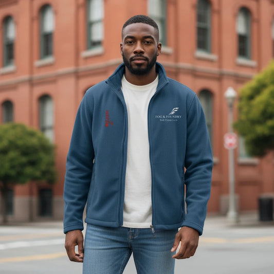 A man wearing a blue Fog & Foundry full-zip polyester fleece jacket with a stand-up collar in an urban setting.