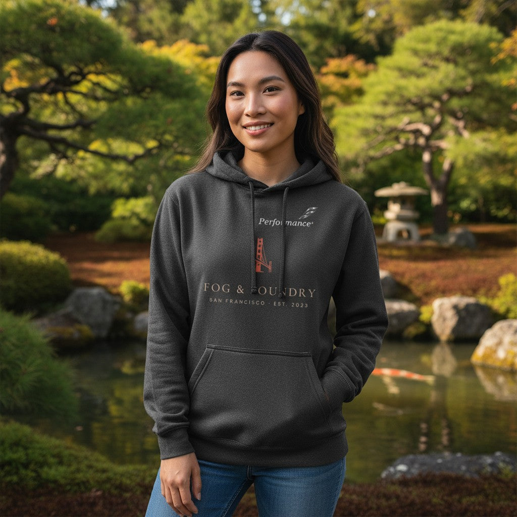 Woman wearing a charcoal grey Fog & Foundry cotton fleece hoodie with a San Francisco graphic in a garden setting.