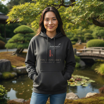 Woman wearing a charcoal Fog & Foundry San Francisco hoodie with a front pouch pocket in a serene garden setting.