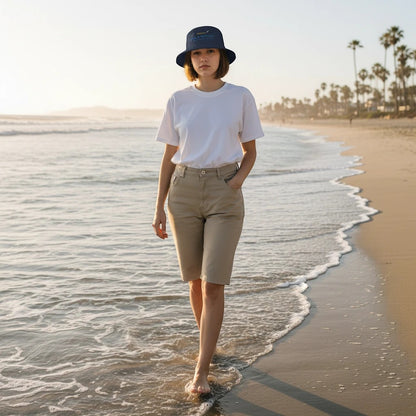 Woman wearing a Fog & Foundry cotton twill bucket hat walking along the beach at sunset.