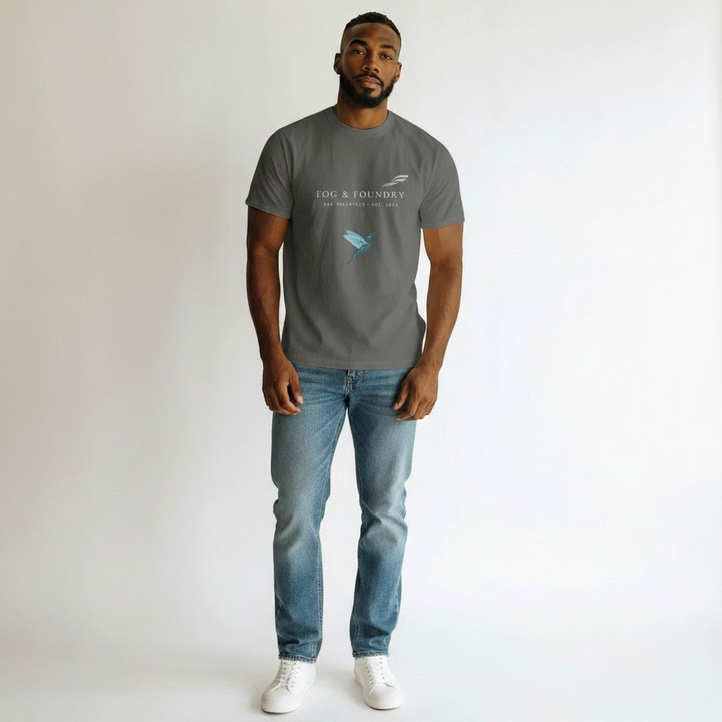 A man wearing a Fog & Foundry gray v-neck cotton t-shirt with a small logo, paired with blue jeans and white sneakers.