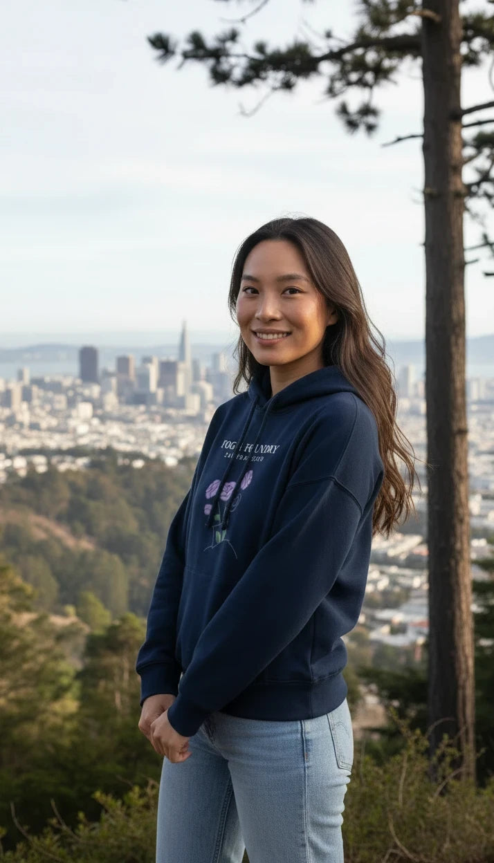 Woman wearing a Fog & Foundry navy organic cotton mid-length hoodie with a floral graphic, standing in San Francisco.