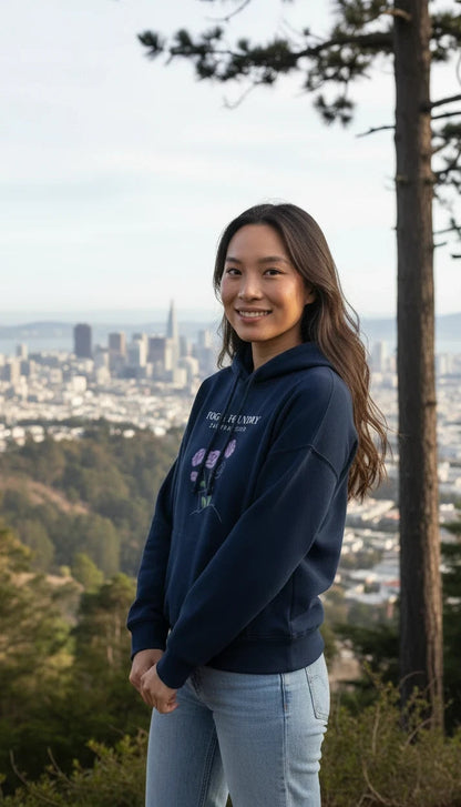 Woman wearing a Fog & Foundry navy organic cotton mid-length hoodie with a floral graphic, standing in San Francisco.