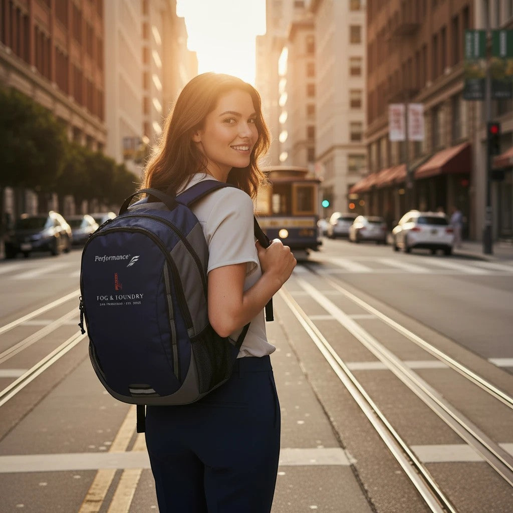 Woman wearing a navy Fog & Foundry Ridge backpack on a sunny San Francisco street with a cable car in the background.
