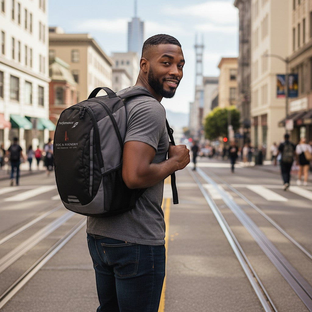 Man wearing a Fog & Foundry black and grey Ridge backpack while walking on a city street with cable car tracks.