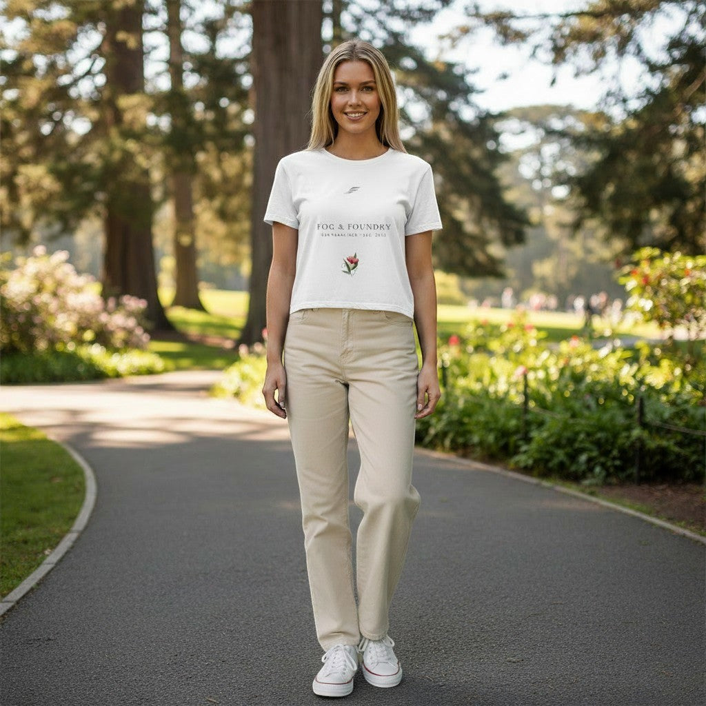 Woman wearing a white Fog & Foundry cropped tee with a hand-drawn bloom graphic in a park setting.