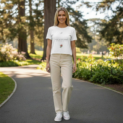 Woman wearing a white Fog & Foundry cropped tee with a hand-drawn bloom graphic in a park setting.