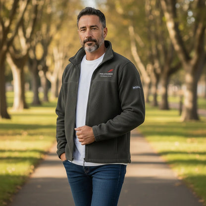 A man wearing a dark green Columbia fleece jacket from Fog & Foundry, featuring a full-zip front in a park setting.