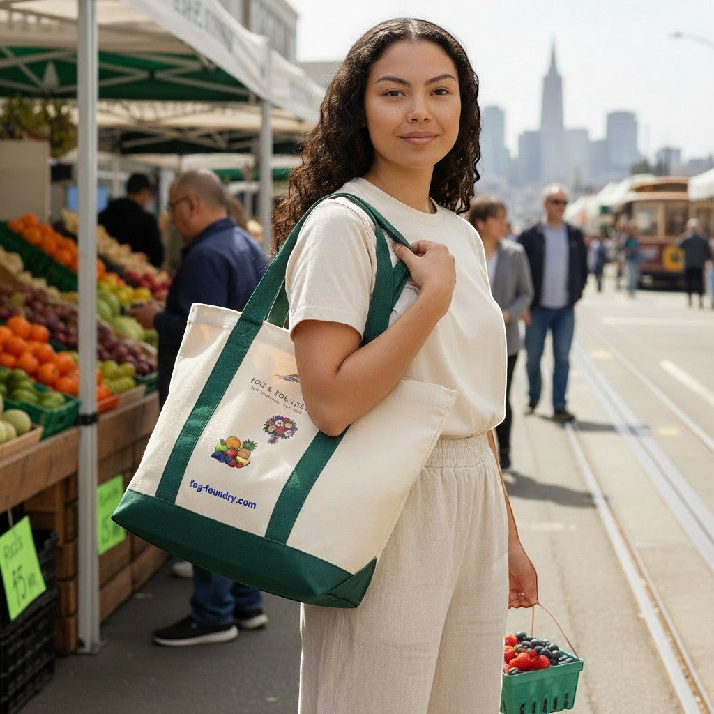 Woman carrying a Fog & Foundry heavyweight cotton twill tote bag with a green canvas base at a sunny outdoor market.