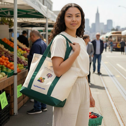 Woman carrying a Fog & Foundry heavyweight cotton twill tote bag with a green canvas base at a sunny outdoor market.