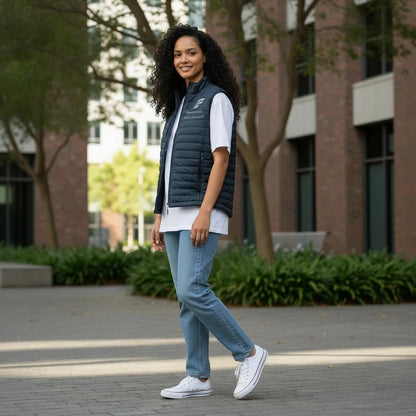 A woman wearing a Fog & Foundry quilted navy marina vest over a white t-shirt and blue jeans in an urban setting.