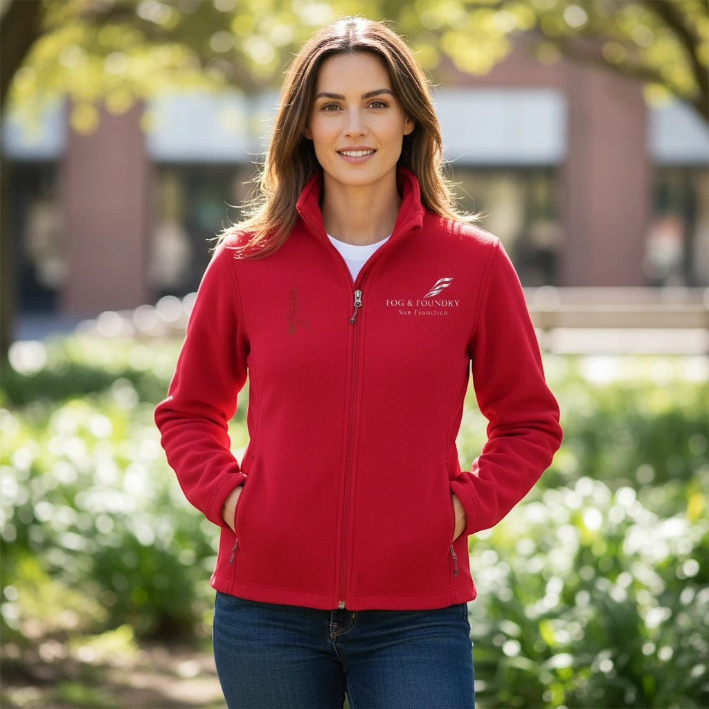 Woman wearing a red Fog & Foundry full-zip fleece jacket with a stand-up collar and zippered pockets outdoors.