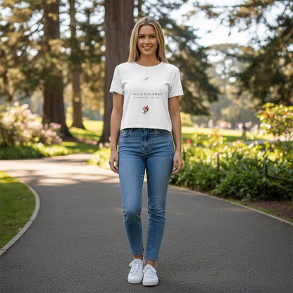 Woman wearing a white Fog & Foundry crop tee with a hand-drawn bloom graphic, styled with blue jeans in a park.