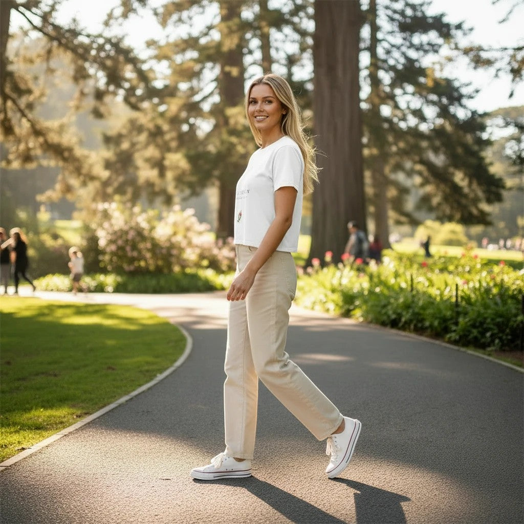 Woman wearing a Fog & Foundry white crop tee with a bloom print, styled with beige trousers in a park setting.