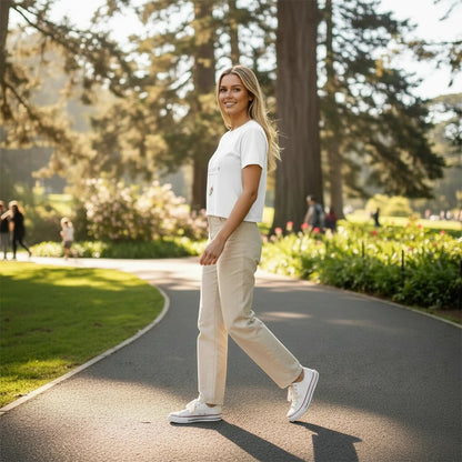Woman wearing a Fog & Foundry white crop tee with a bloom print, styled with beige trousers in a park setting.